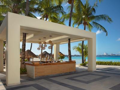 Nowoczesny pawilon na plaży z drewnianym barem i widokiem na palmy i morze.