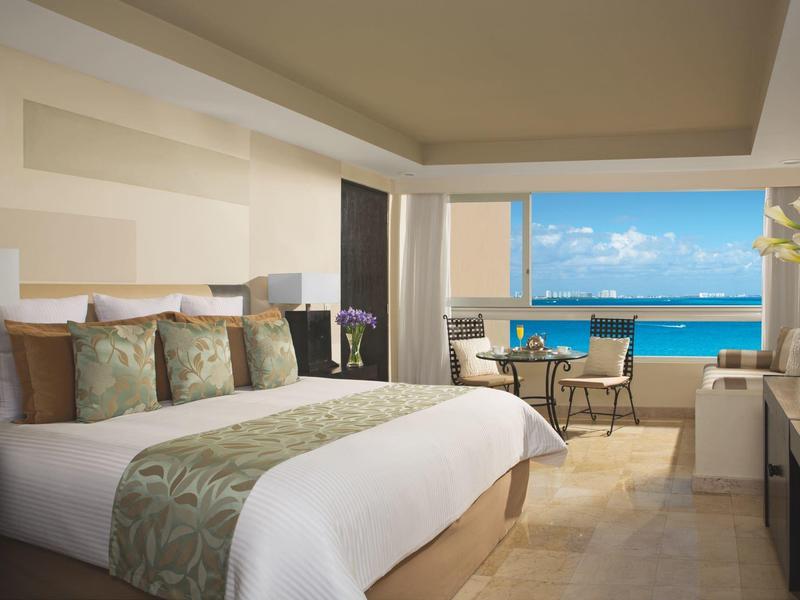 Camera d'hotel moderna con letto grande e vista sull'oceano tramite una grande finestra.