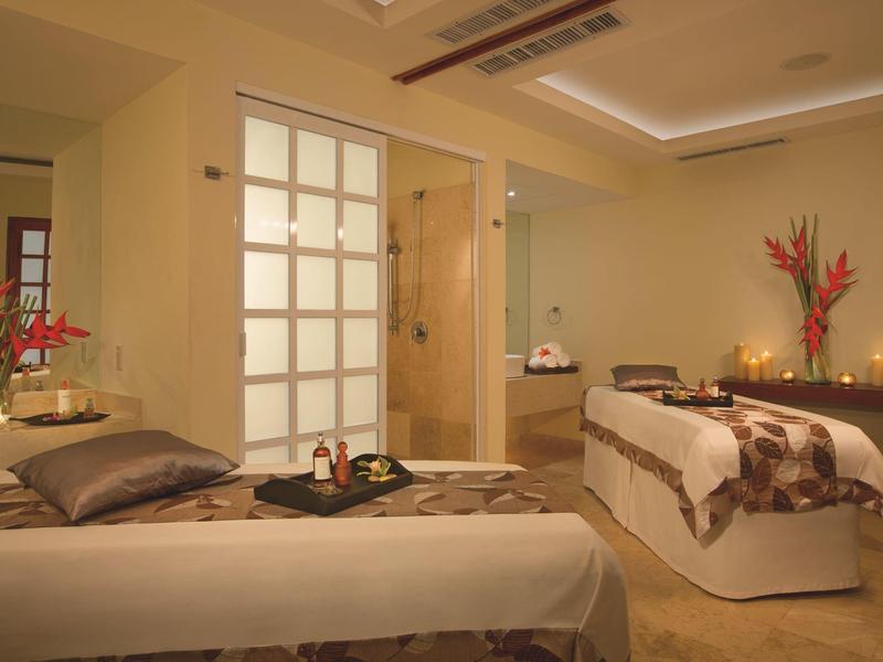 Elegante stanza spa con due lettini da massaggio, illuminazione soffusa e composizioni floreali fresche.