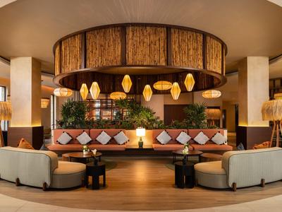 Salon d'hôtel confortable avec canapés modernes, accents en bois et éclairage chaleureux.
