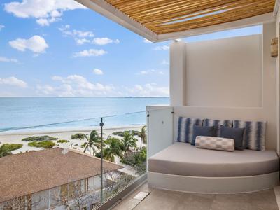 Balcon avec coin salon confortable et vue sur la mer sous un ciel clair.