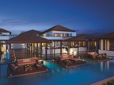 Luxuriöse Bungalows über Wasser mit Beleuchtung bei Dämmerung.