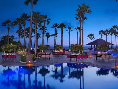 Entspannter Poolbereich bei Sonnenuntergang mit Palmen und komfortablen Sitzbereichen.