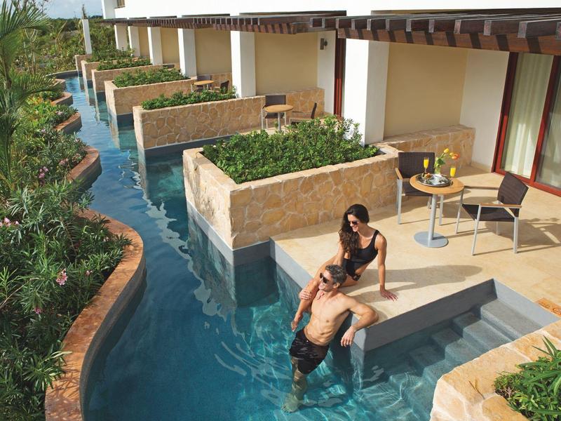 Camere del resort che si affacciano su una piscina con lettini e vegetazione tra le unità.