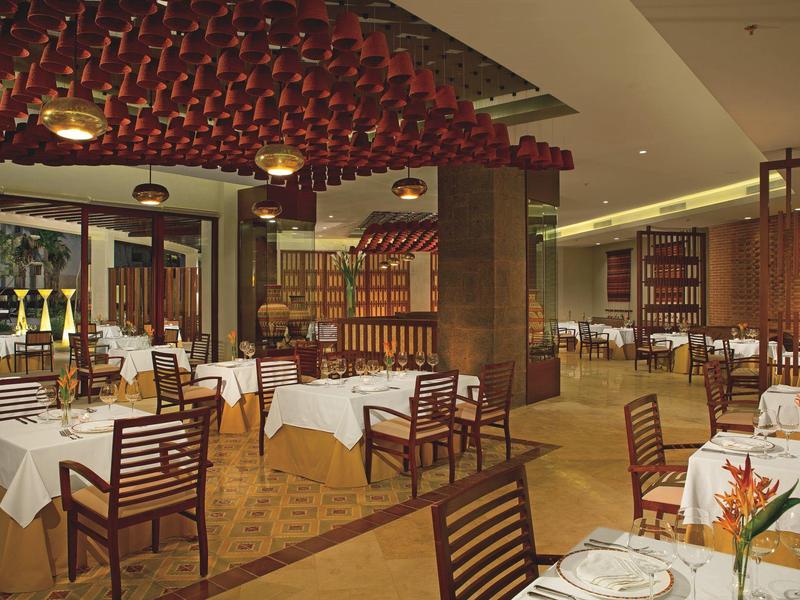 Ristorante d'hotel elegante con sedie di legno, tovaglie bianche e illuminazione calda.