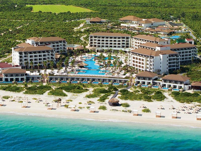 Un grande resort sulla spiaggia con più piscine e file di lettini sul mare.