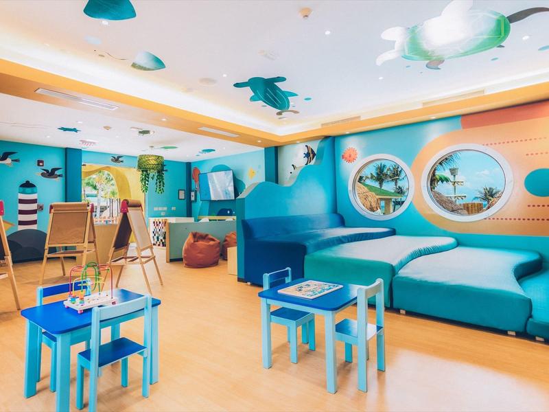 Kolorowy kącik zabaw dla dzieci z wygodnymi miejscami do siedzenia i artystycznymi dekoracjami ściennymi.