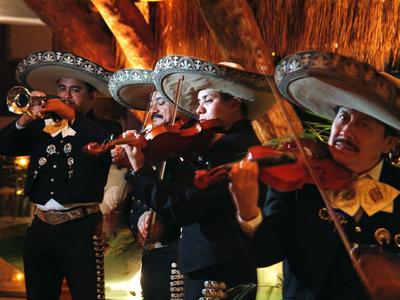 Zespół mariachi gra tradycyjne instrumenty podczas wieczornego wydarzenia z ciepłym oświetleniem.