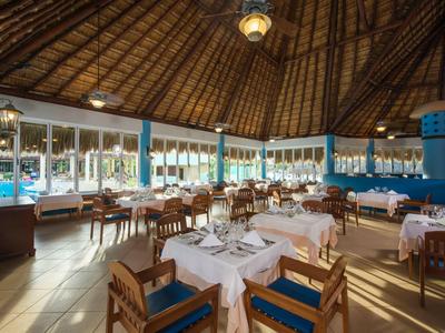 Ristorante in hotel tropicale con mobili in legno e vista sulla piscina.
