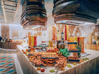 Bufet z różnorodnym jedzeniem i napojami w jasnym, dekoracyjnym pomieszczeniu.