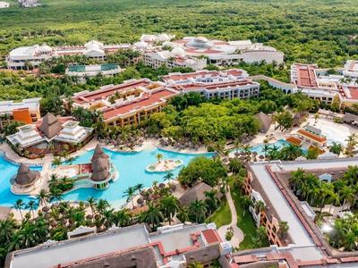 Vista aerea di un resort tropicale con più piscine, vegetazione rigogliosa e edifici.