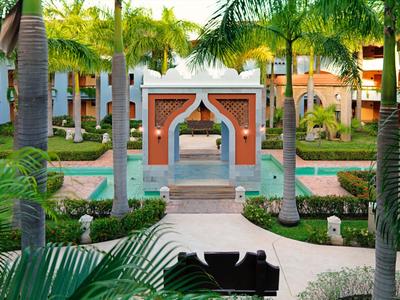 Giardino dell'hotel con palme, sentieri curati e un arco decorativo in stile marocchino.