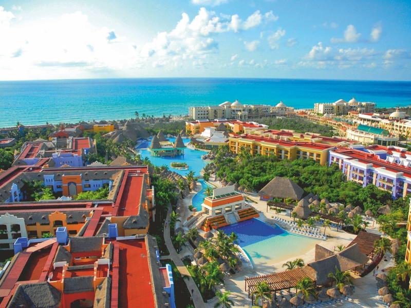Grande complesso alberghiero con più piscine e vista sul mare azzurro sotto un cielo sereno.
