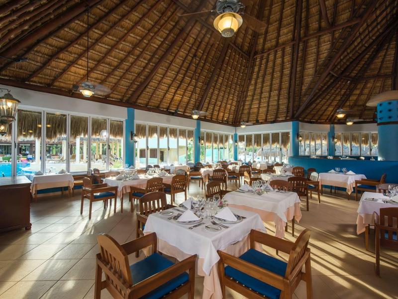 Ristorante in hotel tropicale con mobili in legno e vista sulla piscina.