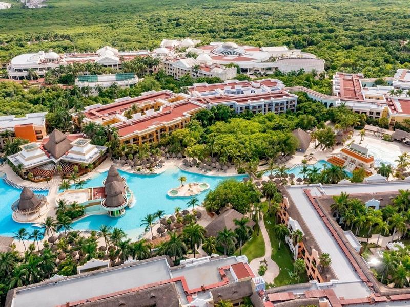Vista aerea di un resort tropicale con più piscine, vegetazione rigogliosa e edifici.