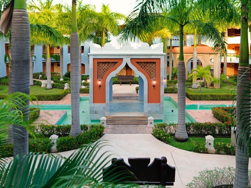 Giardino dell'hotel con palme, sentieri curati e un arco decorativo in stile marocchino.