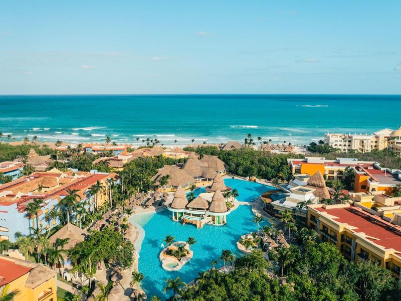 Vista di un resort con grande piscina, vegetazione tropicale e accesso diretto al mare.