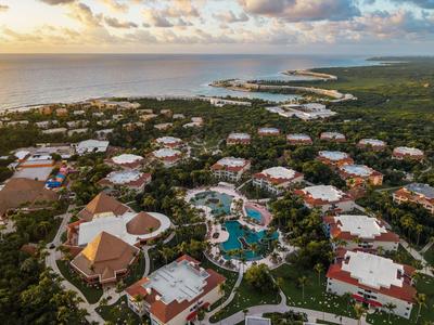 Veduta aerea di un resort con diversi edifici e una piscina centrale vicino al mare.