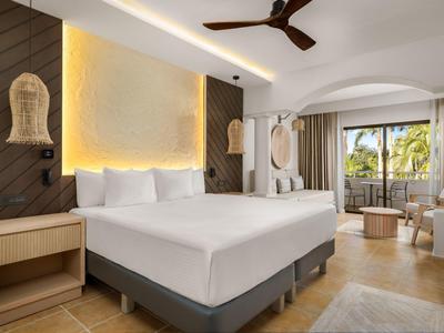 Camera d'albergo moderna con letto grande, dettagli in legno e balcone con vista su palme.