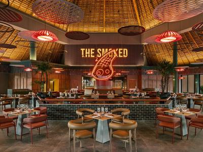 Ristorante moderno con bancone rotondo, sedie in legno e illuminazione misteriosa al soffitto.