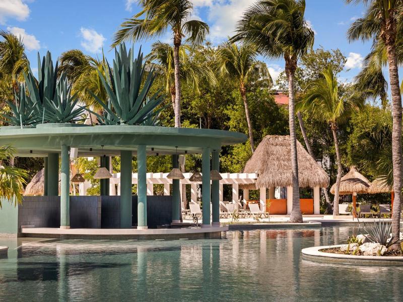 Bar a bordo piscina con palme e tetto di paglia in resort tropicale