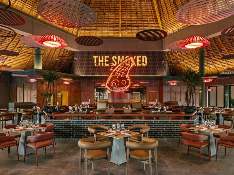 Ristorante moderno con bancone rotondo, sedie in legno e illuminazione misteriosa al soffitto.