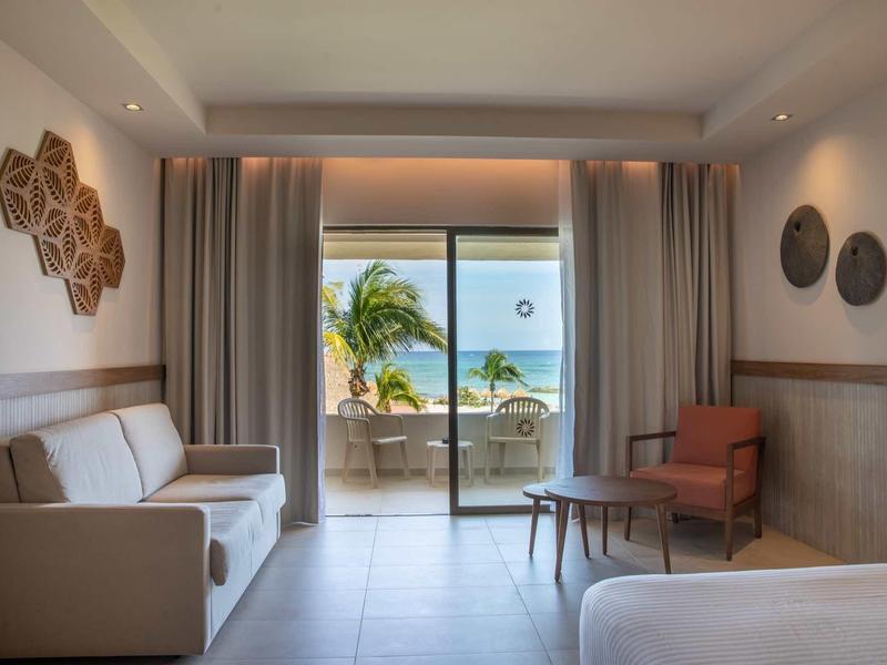 Camera d'hotel moderna con vista mare e terrazza con piante e mobili.