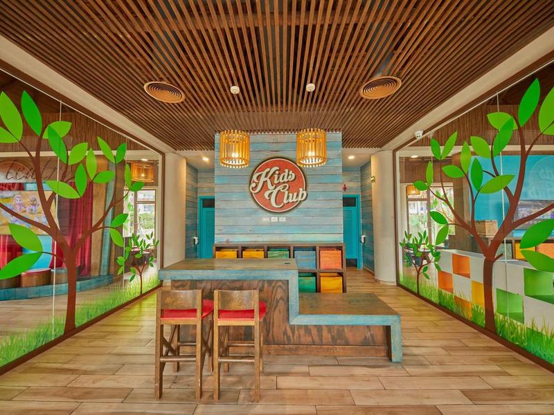 Bar dell'hotel colorata con mobili in legno, decorazioni floreali e illuminazione moderna.