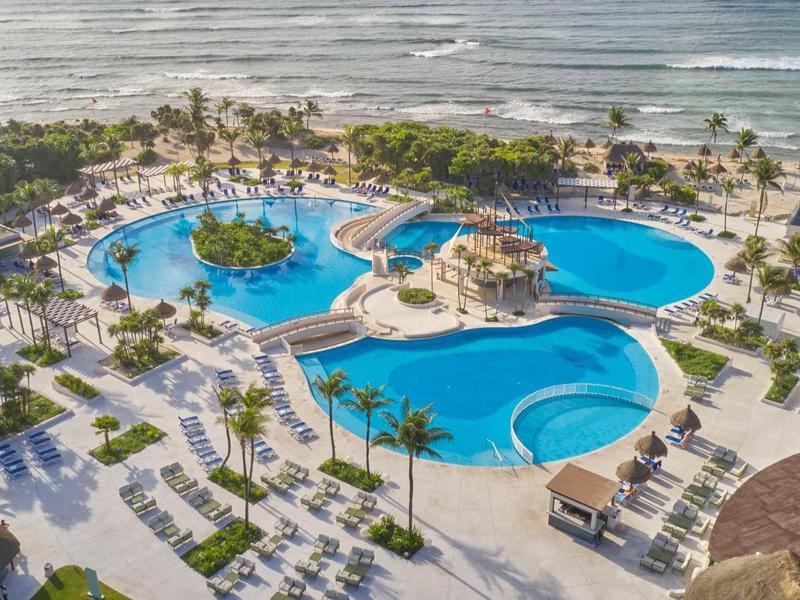 Grande piscina dell'hotel con palme e vista sul mare in un resort tropicale.