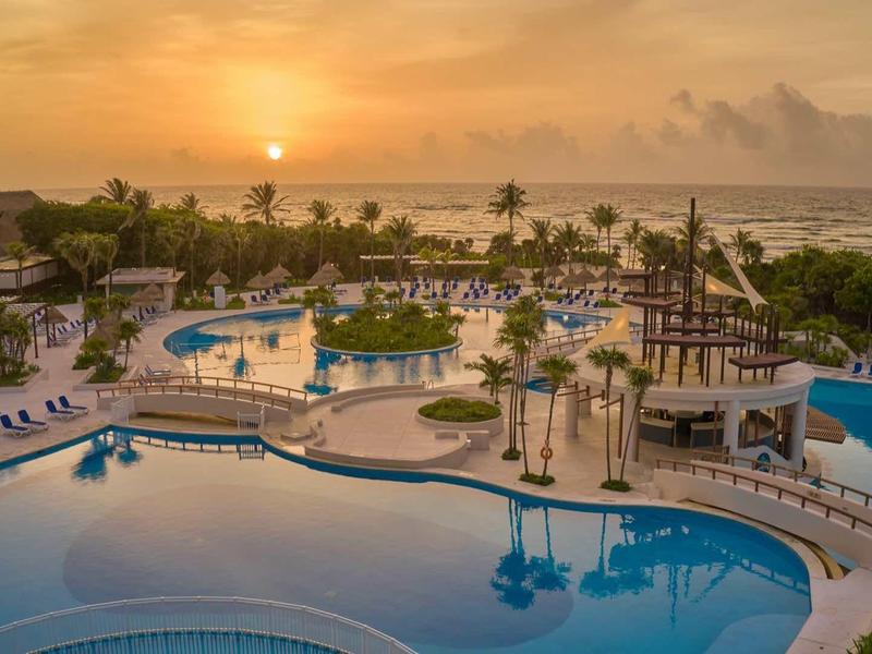 Grande piscina dell'hotel con lettini e palme al tramonto vicino al mare