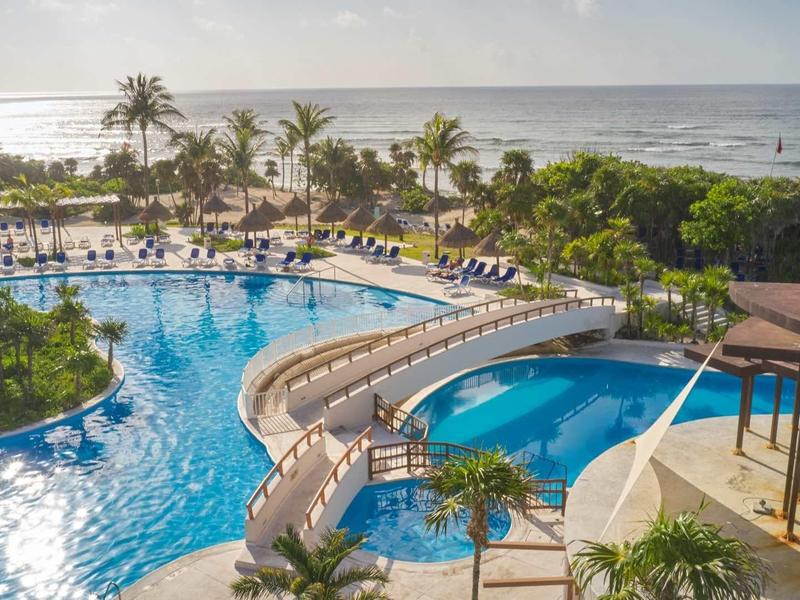 Grande piscina con scivoli e palme in un resort tropicale sul mare.