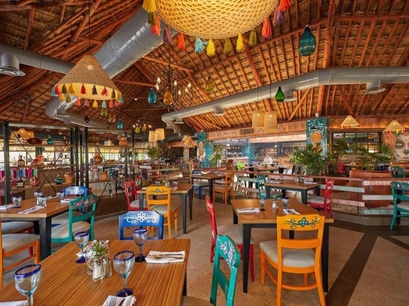 Ristorante decorato colorato con tetto in legno e sedie multicolori