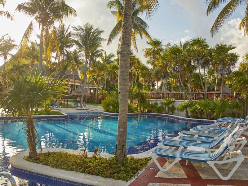 Area piscina con lettini e palme in un resort tropicale al tramonto