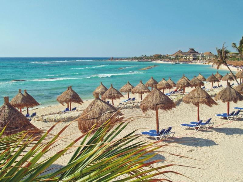 Spiaggia sabbiosa con lettini blu e ombrelloni di paglia vicino al mare