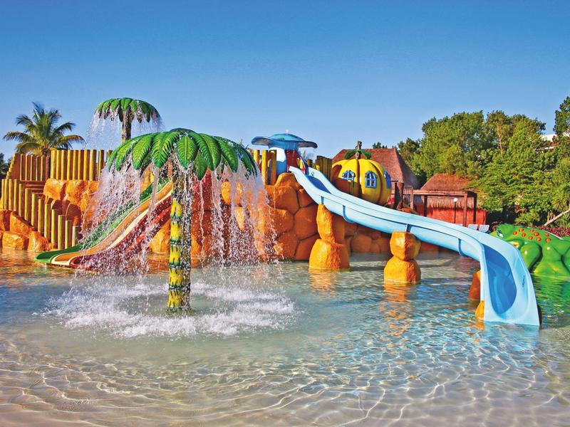 Scivolo d'acqua colorato e fontana in un parco acquatico sotto un cielo limpido.
