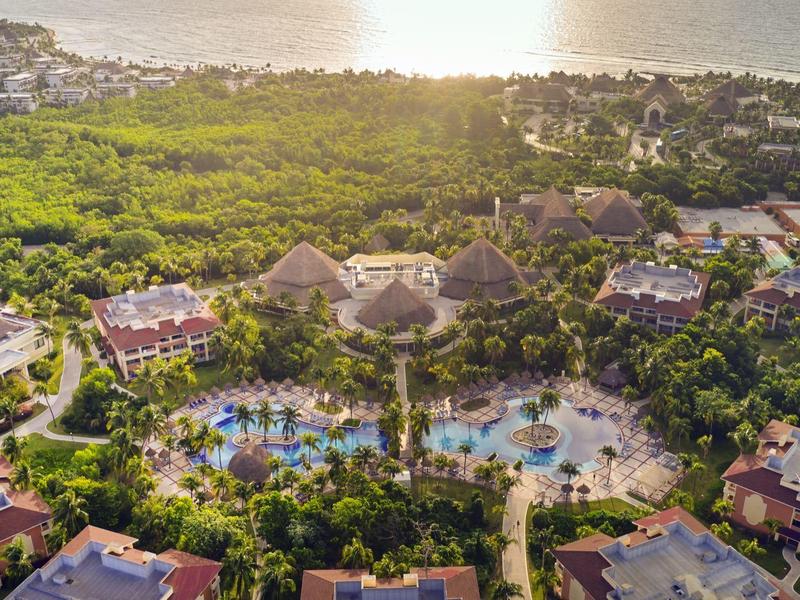 Vista aerea di un resort con piscina, circondato da molta vegetazione vicino al mare.