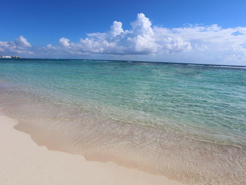 Spiaggia limpida con sabbia bianca e acqua turchese sotto il cielo azzurro.