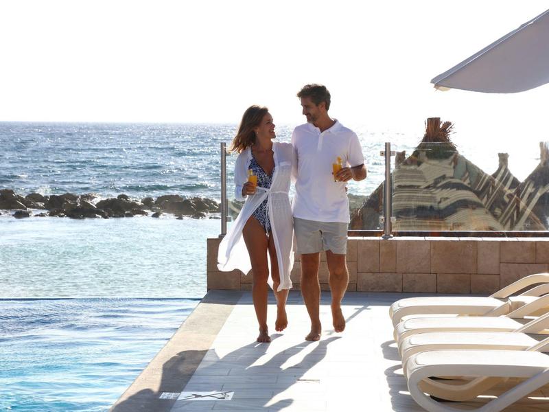 Coppia che cammina accanto alla piscina vicino al mare, giornata di vacanza rilassante vicino all'acqua.