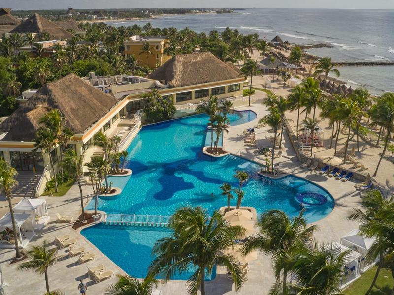 Hotel di lusso con grande piscina, palme e vista sull'oceano sulla costa.