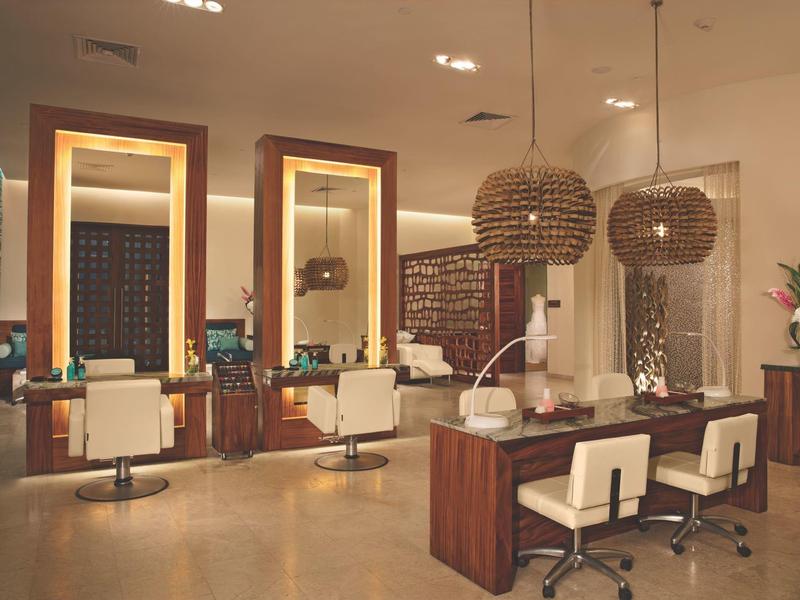 Interno moderno di un salone di parrucchiere con specchi, sedie e lampade a luce calda.