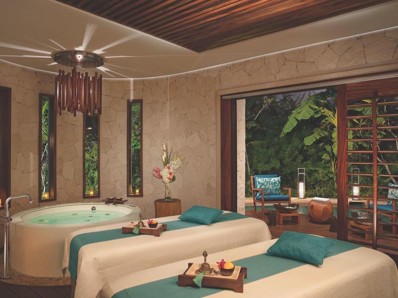 Sala spa di lusso con due lettini da massaggio e vasca idromassaggio, vista sul giardino