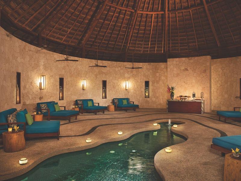 Elegante area spa con soffitto rotondo in legno, piscina interna e lettini blu.