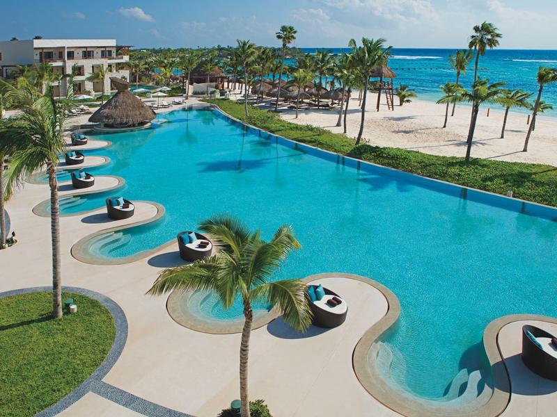 Area piscina lussuosa con lettini confortevoli e sfondo di spiaggia tropicale.