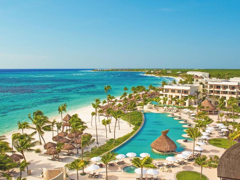 Resort di lusso con piscina tropicale, palme e vista sul mare turchese.