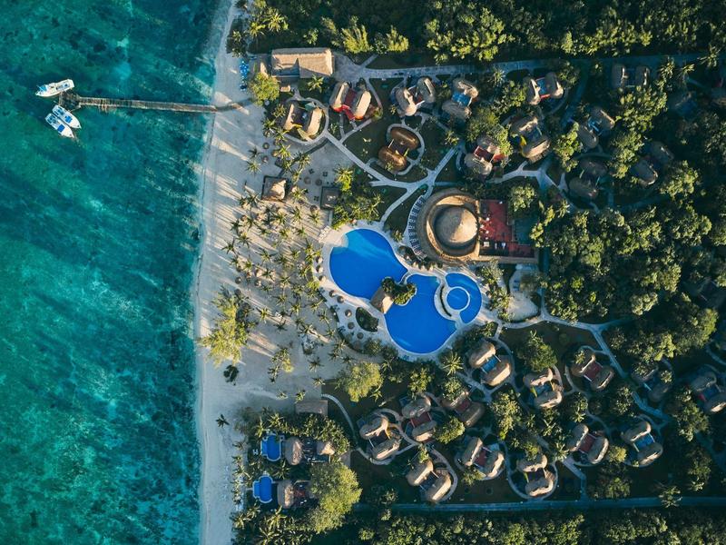 Vista aerea di un resort con piscina e bungalow sulla spiaggia accanto ad acqua turchese