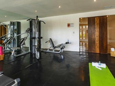 Palestra moderna con attrezzi e tappetino yoga verde in hotel