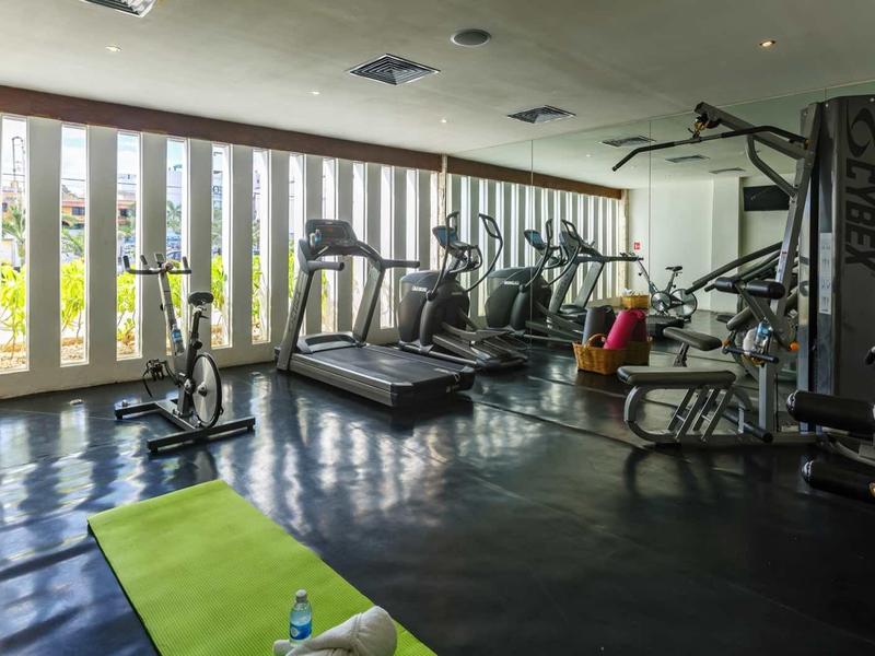 Palestra moderna con attrezzi, pesi e grande finestra che lascia entrare la luce naturale.