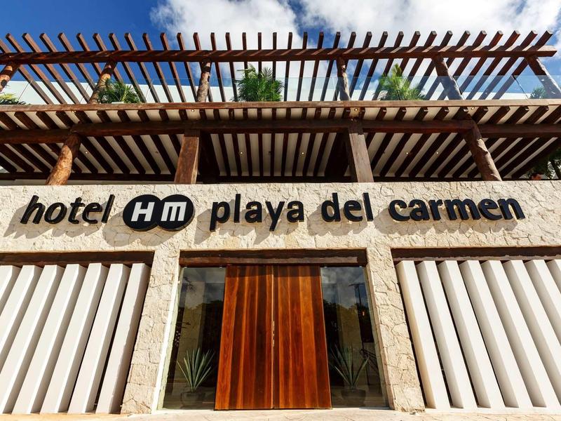 Facciata dell'Hotel HM Playa del Carmen con finiture in legno e design moderno.