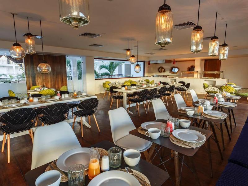 Sala da pranzo elegante con mobili moderni e tavoli apparecchiati in luce calda.