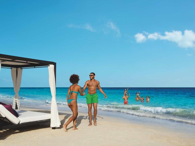 Coppia che trascorre del tempo su una spiaggia soleggiata con cielo sereno e mare blu.